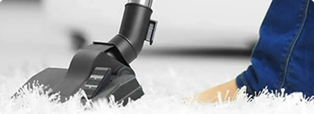 Close-up of a professional vacuuming a white carpet in Hialeah.